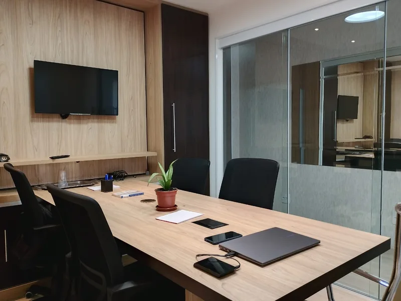 Sala de reuniões da Machia, com mesa de madeira e divisória de vidro